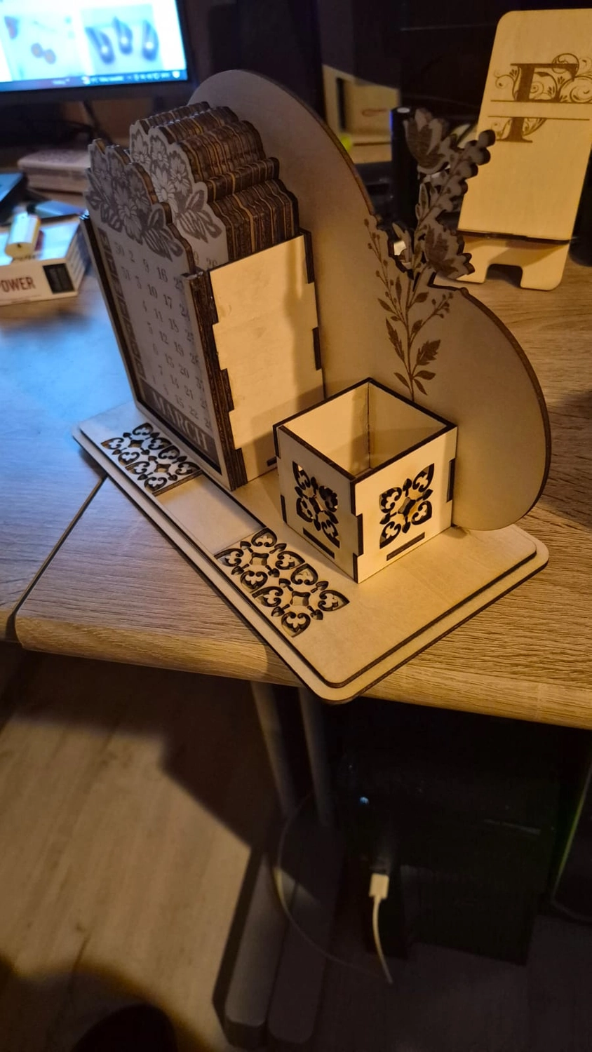 Dach,Wand und Holzkonstruktion - Handgefertigte Holzkunst - Ein lasergeschnittener Schreibtisch-Organizer aus Holz mit geometrischen Mustern und einem kleinen Stiftehalter.