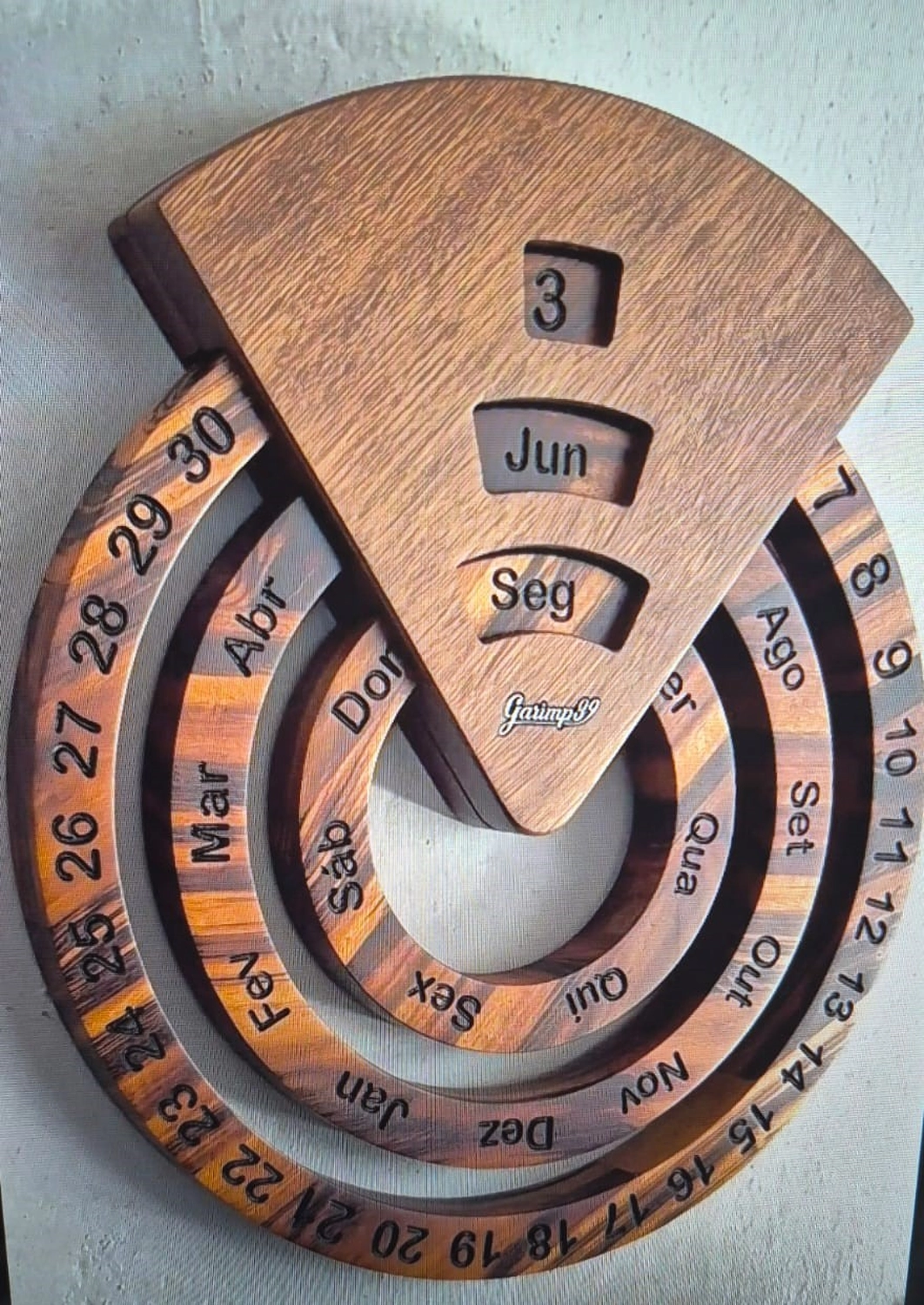 Dach,Wand und Holzkonstruktion - Handgefertigte Holzkunst - Ein runder, ewiger Kalender aus Schichtholz mit drehbaren Ringen zur Anzeige von Tag, Datum und Monat.