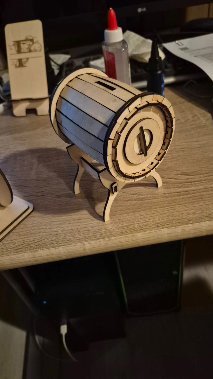 Dach,Wand und Holzkonstruktion - Handgefertigte Holzkunst - Eine kleine, zylindrische Spardose oder ein Fass aus lasergeschnittenen Sperrholzleisten auf einem passenden Ständer.