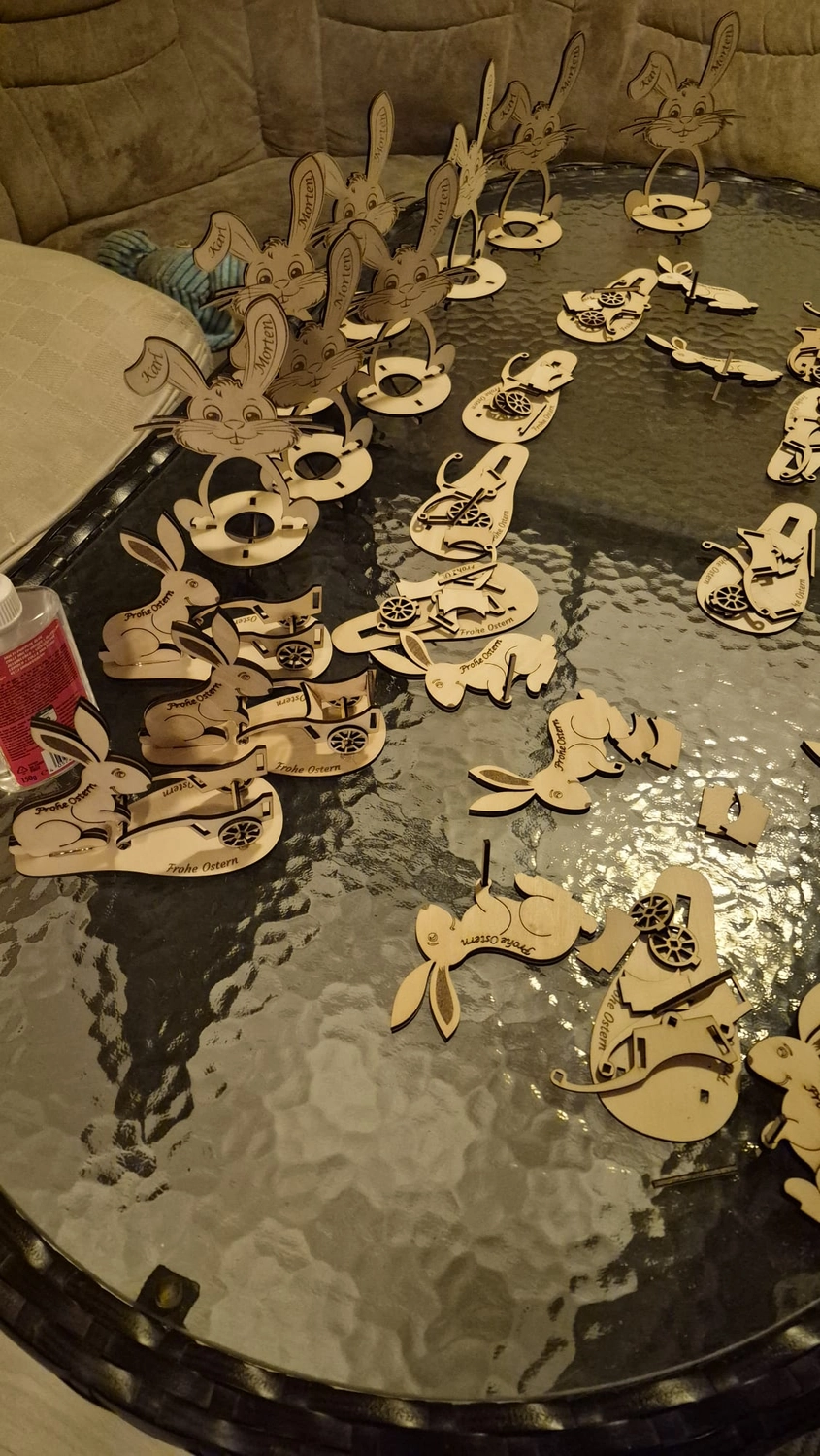 Dach,Wand und Holzkonstruktion - Handgefertigte Holzkunst - Verschiedene lasergeschnittene Hasenfiguren aus Holz auf einer dunklen Fläche.