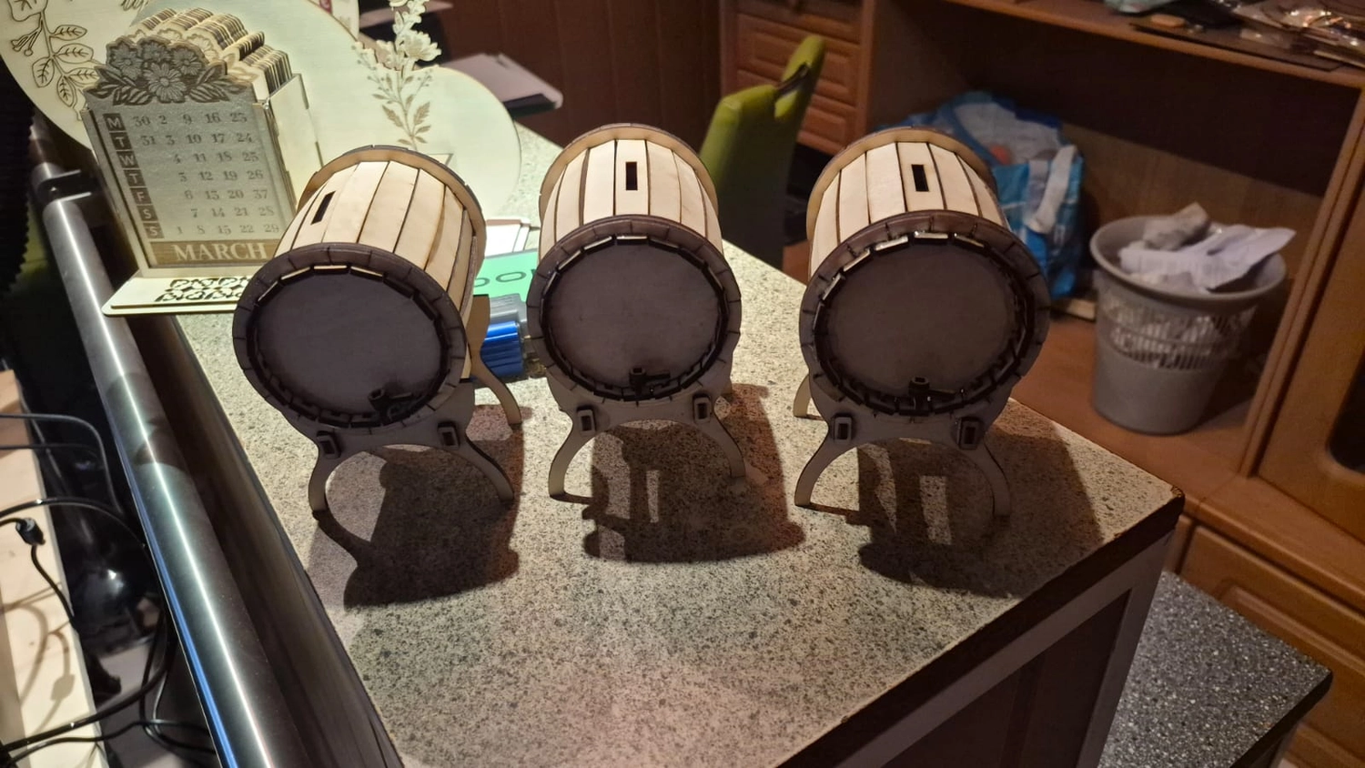 Dach,Wand und Holzkonstruktion - Handgefertigte Holzkunst - Drei kleine, fassförmige Holzbehälter auf einer gesprenkelten Arbeitsplatte.