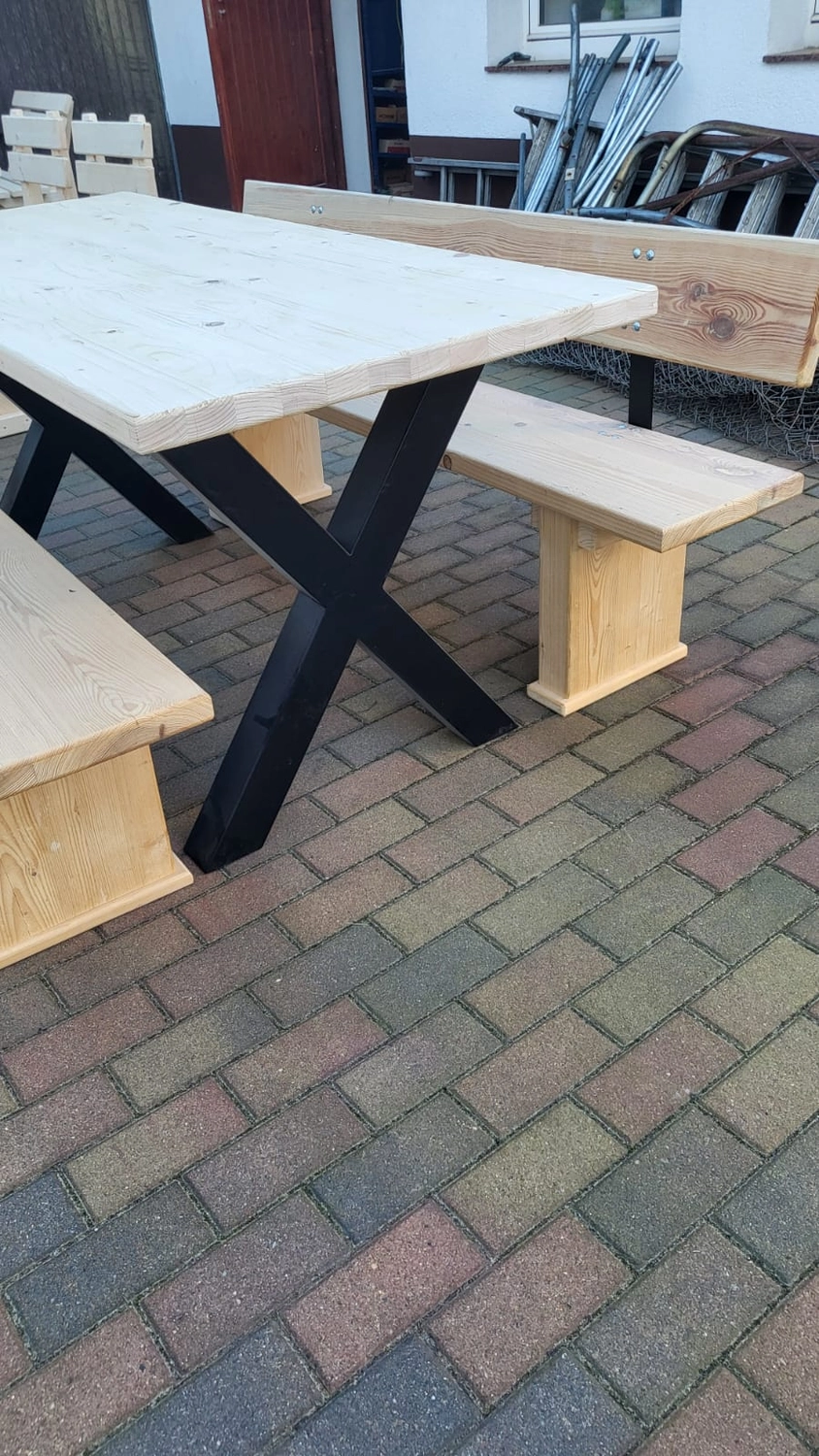 Dach,Wand und Holzkonstruktion - Handgefertigte Holzkunst - Ein moderner Picknicktisch mit weißer Steinplatte, schwarzen X-förmigen Metallbeinen und passenden hellen Holzbänken.