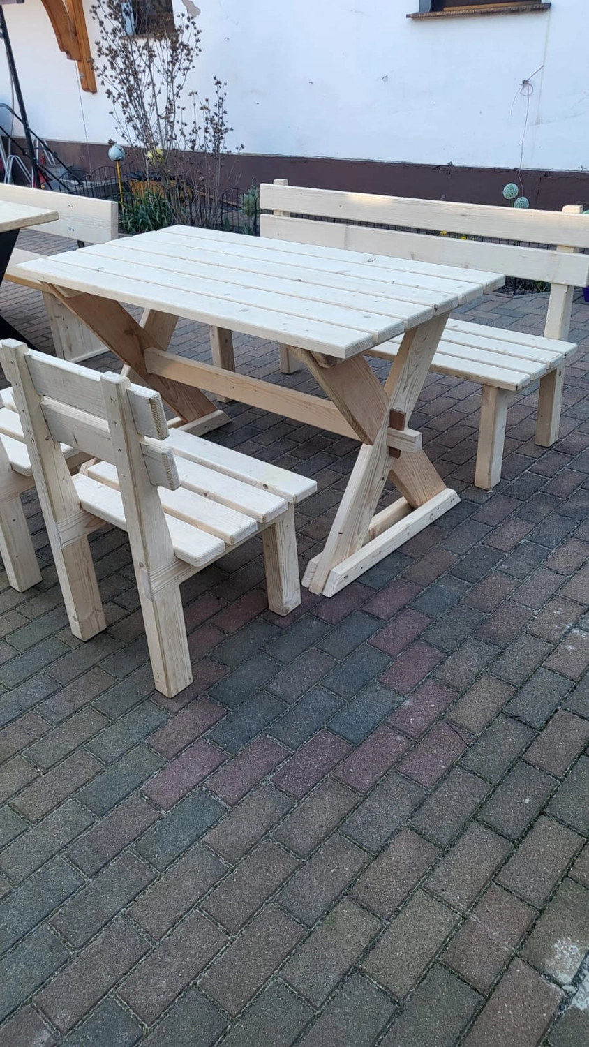 Dach,Wand und Holzkonstruktion - Handgefertigte Holzkunst - Eine helle Essgruppe aus Holz für den Außenbereich, bestehend aus einem rechteckigen Picknicktisch mit passenden Bänken und einem Stuhl.