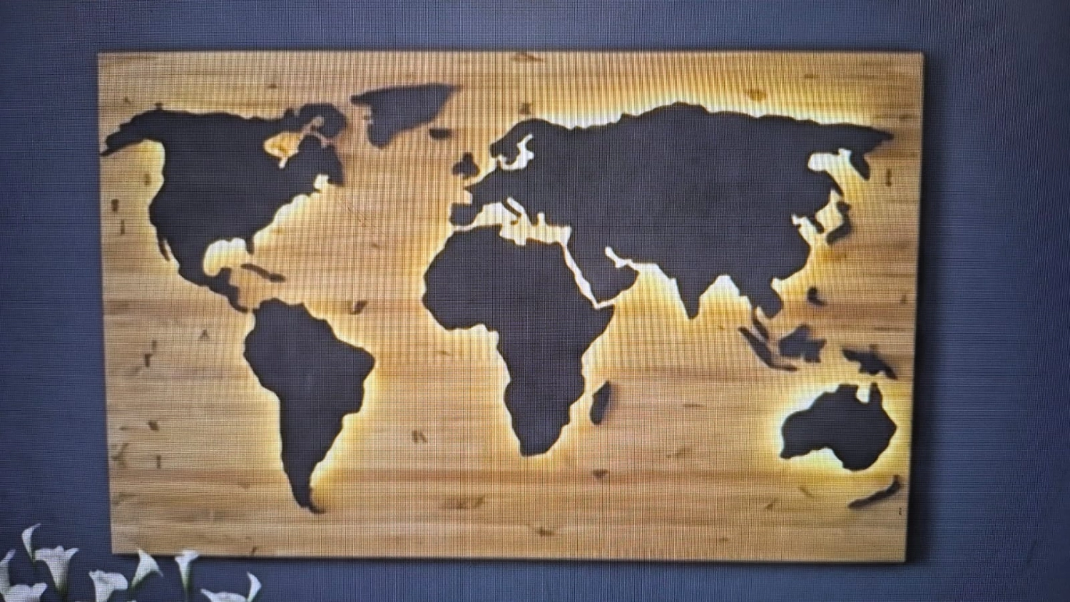 Dach,Wand und Holzkonstruktion - Handgefertigte Holzkunst - Eine große hölzerne Weltkarte mit dunkel gebeizten Kontinenten und hinterleuchteten Rändern für einen Leuchteffekt.