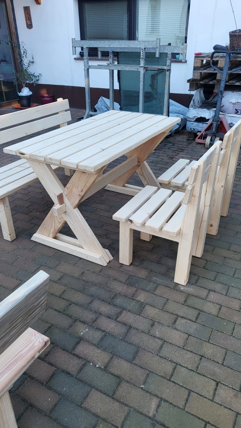 Dach,Wand und Holzkonstruktion - Handgefertigte Holzkunst -Eine helle Essgruppe aus Holz für den Außenbereich mit Lattentisch und vier passenden Stühlen.